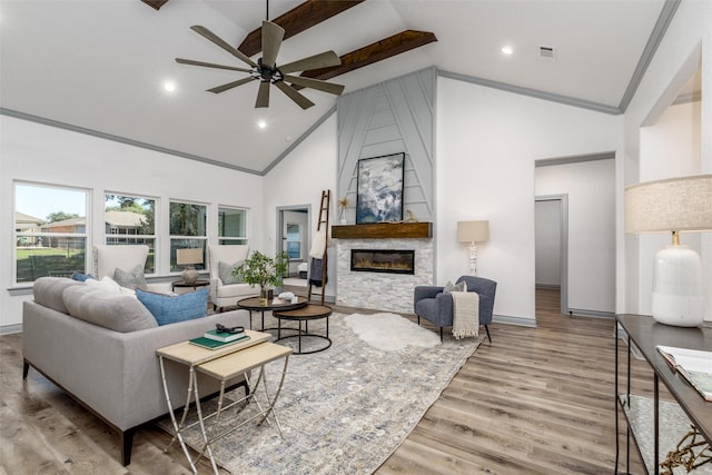 living room featuring high vaulted ceiling, light hardwood / wood-style flooring, ceiling fan, beam ceiling, and a large fireplace