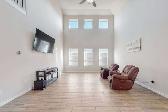 living area featuring a healthy amount of sunlight, ceiling fan, and a towering ceiling