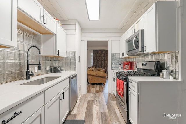 kitchen with white cabinetry, sink, stainless steel appliances, light hardwood / wood-style flooring, and decorative backsplash