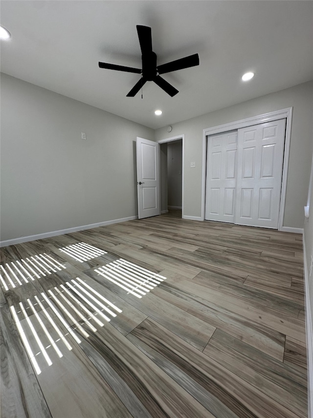 unfurnished bedroom with ceiling fan, wood-type flooring, and a closet