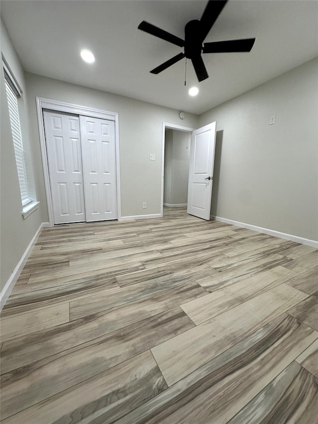 unfurnished bedroom featuring ceiling fan, a closet, and light wood-type flooring