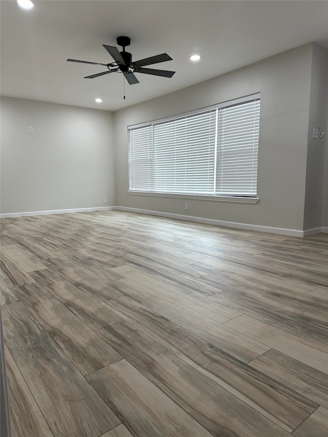 empty room with ceiling fan and light wood-type flooring