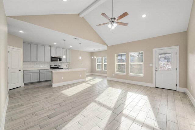 unfurnished living room with plenty of natural light, beam ceiling, sink, and light hardwood / wood-style flooring