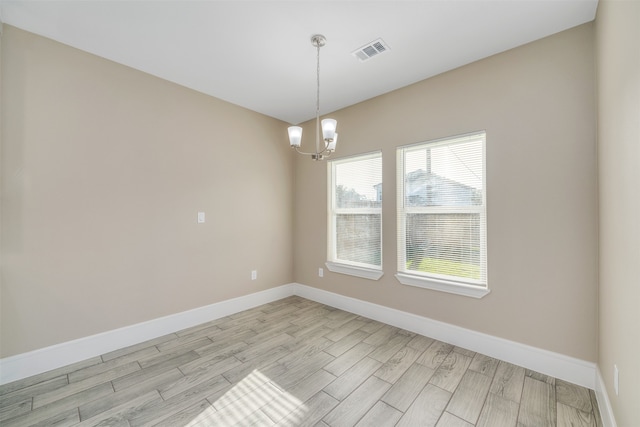 unfurnished room featuring light hardwood / wood-style floors and a chandelier