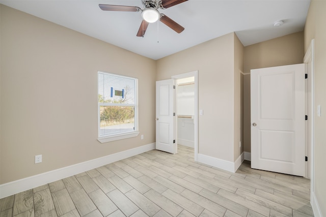 unfurnished bedroom featuring ceiling fan, light hardwood / wood-style floors, a spacious closet, and a closet