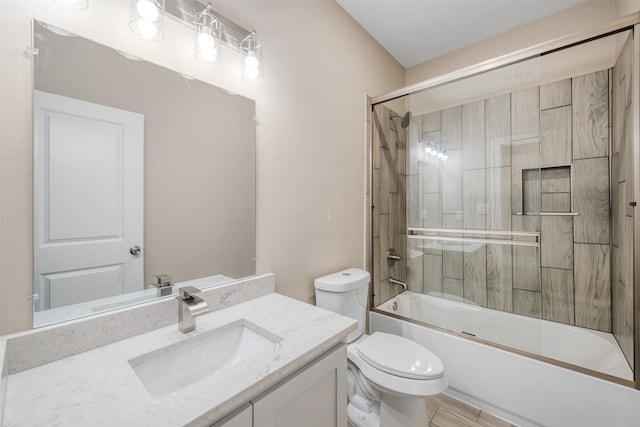 full bathroom with combined bath / shower with glass door, vanity, hardwood / wood-style flooring, and toilet