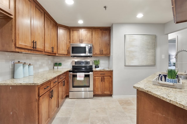 kitchen with decorative backsplash, light tile patterned flooring, light stone counters, and appliances with stainless steel finishes