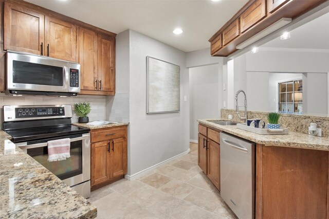 kitchen with decorative backsplash, light stone counters, ornamental molding, stainless steel appliances, and sink