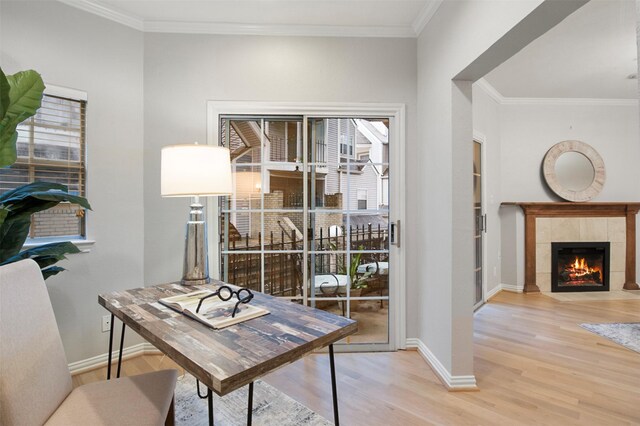 office area with wood-type flooring, ornamental molding, and a tiled fireplace