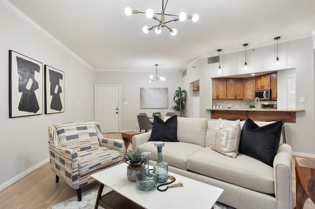 living room with a chandelier, light hardwood / wood-style floors, and ornamental molding