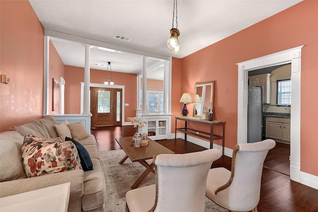 1117 W Bond St, Denison, TX 75020 - living area with ornate columns, dark wood-type flooring, plenty of natural light, and a textured ceiling