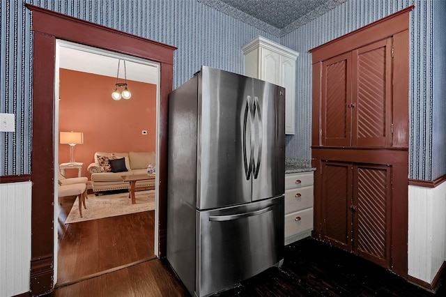 kitchen featuring hanging light fixtures, white cabinets, dark wood-type flooring, and stainless steel refrigerator