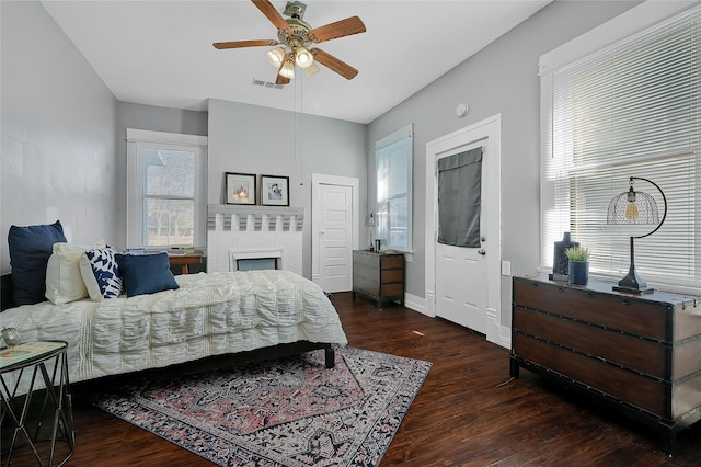 bedroom with ceiling fan, dark hardwood / wood-style floors, and a brick fireplace