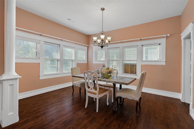 dining area with decorative columns, a textured ceiling, dark hardwood / wood-style floors, and a chandelier