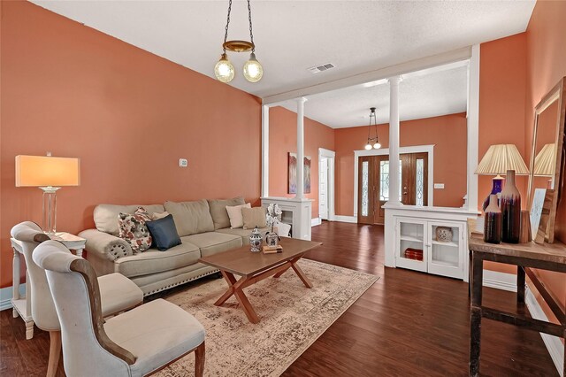 living room with an inviting chandelier, dark hardwood / wood-style flooring, and decorative columns