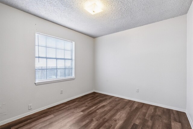 spare room with a textured ceiling and dark hardwood / wood-style floors