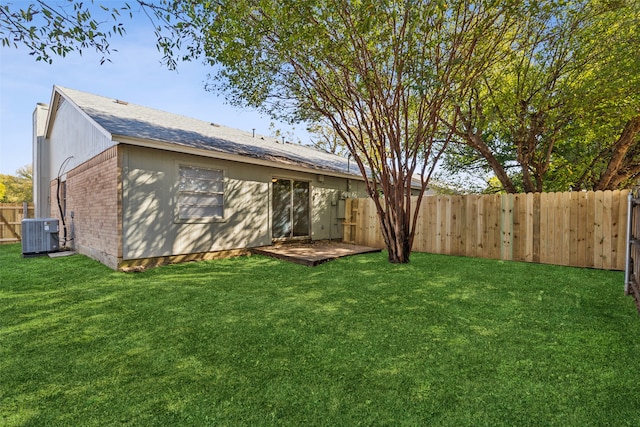 back of property with central AC unit and a yard