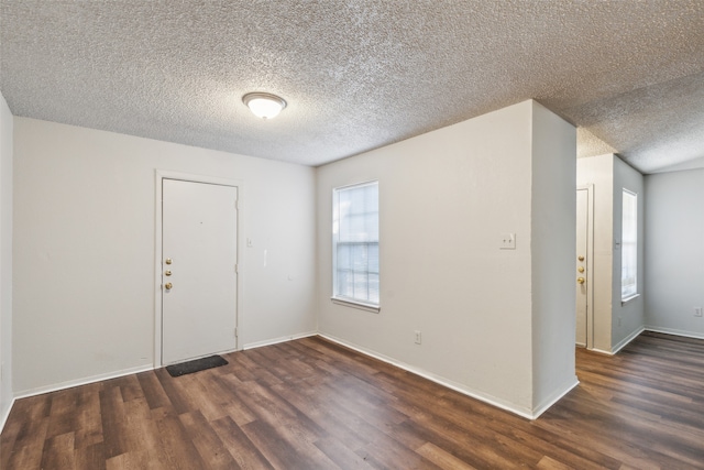 empty room with a textured ceiling and dark hardwood / wood-style floors