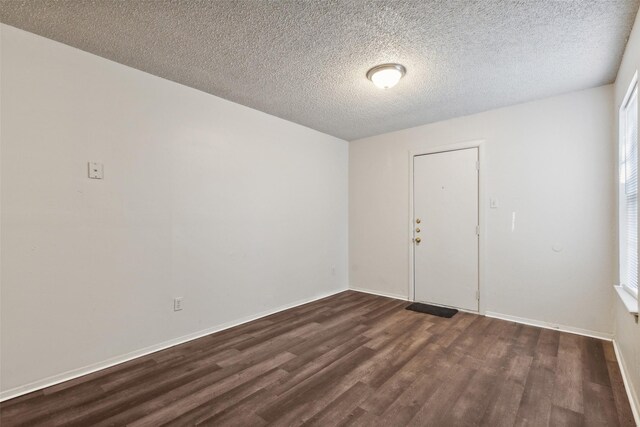 empty room with a textured ceiling and dark hardwood / wood-style floors