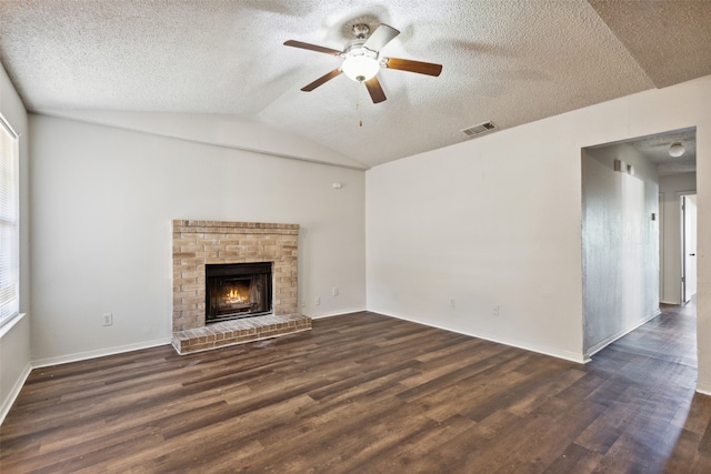 unfurnished living room with ceiling fan, a brick fireplace, dark hardwood / wood-style flooring, a textured ceiling, and lofted ceiling