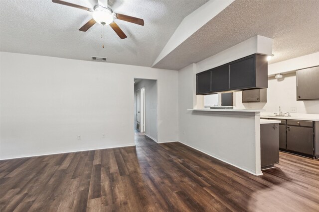 kitchen with kitchen peninsula, ceiling fan, dark hardwood / wood-style floors, and a textured ceiling