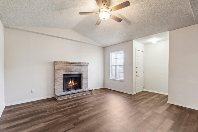 unfurnished living room featuring dark hardwood / wood-style floors, vaulted ceiling, ceiling fan, and a brick fireplace