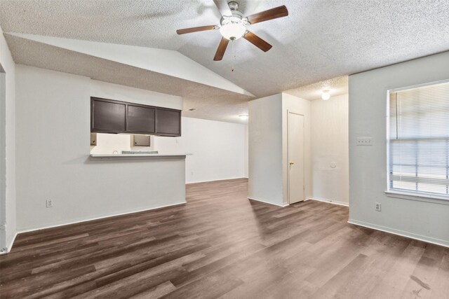 unfurnished living room with a textured ceiling, ceiling fan, dark hardwood / wood-style flooring, and vaulted ceiling