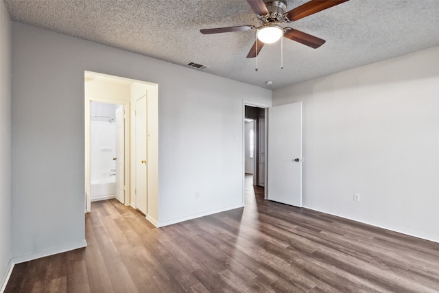 unfurnished bedroom featuring ensuite bath, ceiling fan, wood-type flooring, and a textured ceiling