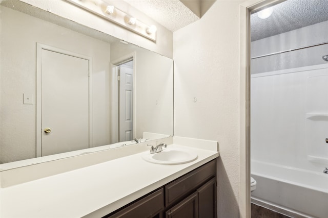 full bathroom featuring vanity, a textured ceiling, toilet, and shower / washtub combination