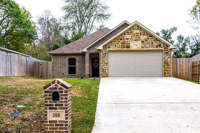206 Willowbrook Ave, Tyler, TX 75702 - view of front of home with driveway, an attached garage, stone siding, and a shingled roof