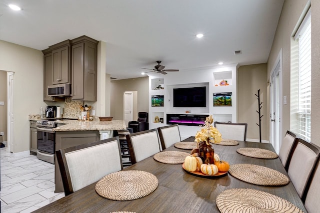 kitchen featuring gray cabinetry, decorative backsplash, ceiling fan, appliances with stainless steel finishes, and light stone counters