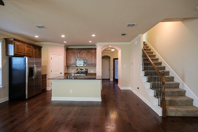 kitchen with backsplash, a center island with sink, crown molding, appliances with stainless steel finishes, and dark hardwood / wood-style flooring