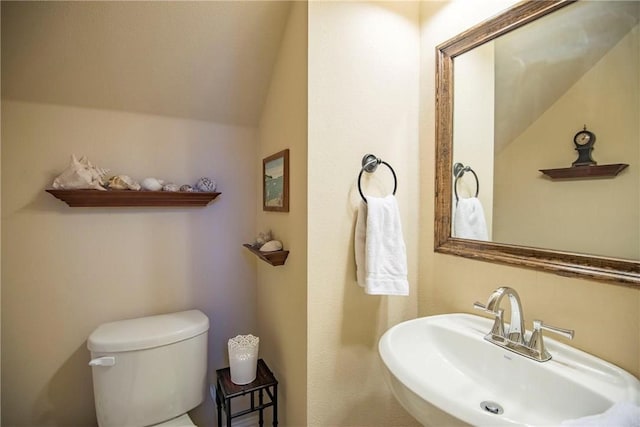 bathroom featuring toilet, sink, and vaulted ceiling