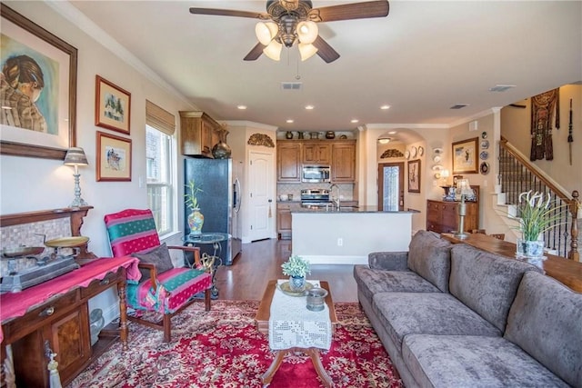 living room featuring dark wood-type flooring, ceiling fan, ornamental molding, and sink