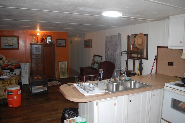 kitchen featuring dark wood-type flooring, sink, electric range, white cabinetry, and wood walls