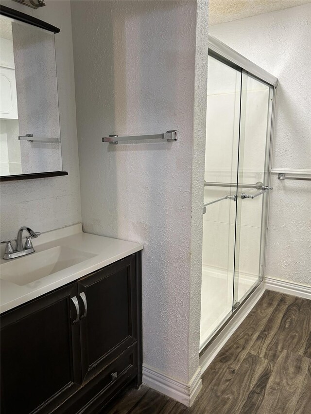 bathroom featuring vanity, wood-type flooring, and a shower with shower door