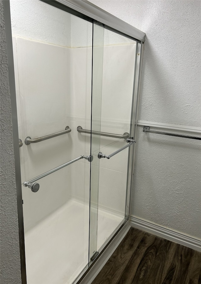 bathroom with hardwood / wood-style flooring and a shower with door