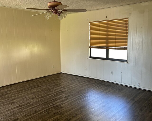 empty room featuring dark hardwood / wood-style floors, ceiling fan, a textured ceiling, and wooden walls