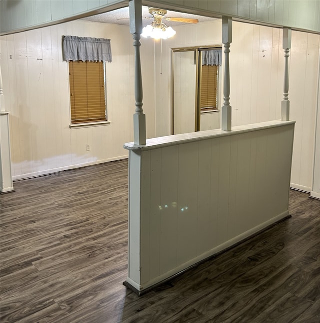 interior space with dark hardwood / wood-style floors, wood walls, and ceiling fan