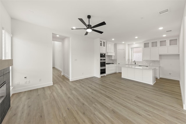 3100 Summer Rain Ln, Anna, TX 75409 - unfurnished living room with a tiled fireplace, a ceiling fan, recessed lighting, and light wood finished floors