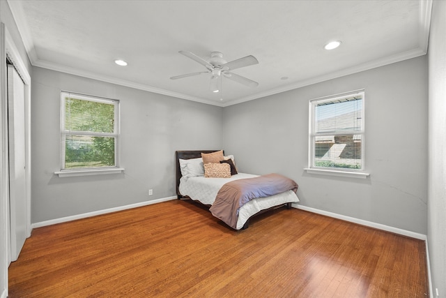 bedroom featuring a closet, hardwood / wood-style flooring, ceiling fan, and ornamental molding