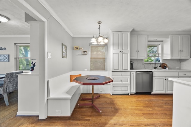 kitchen with stainless steel dishwasher, pendant lighting, light wood-type flooring, and an inviting chandelier