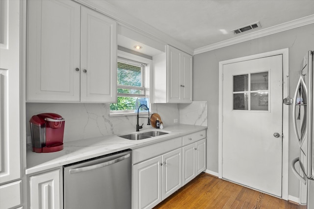 kitchen with appliances with stainless steel finishes, light wood-type flooring, white cabinetry, and sink