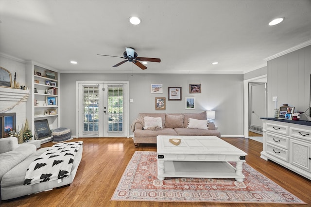 living room with french doors, a brick fireplace, ceiling fan, ornamental molding, and light hardwood / wood-style floors