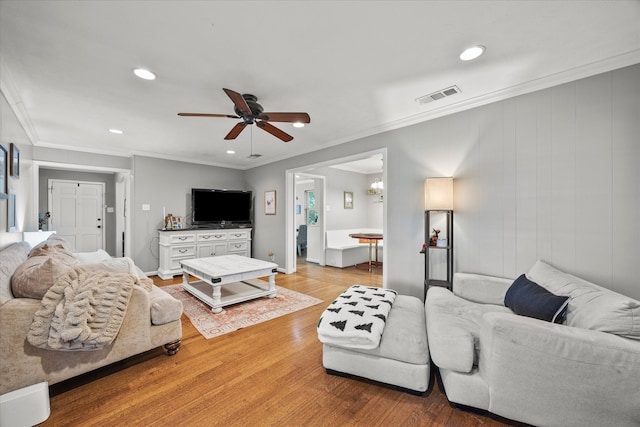 living room featuring hardwood / wood-style floors, ceiling fan, and crown molding