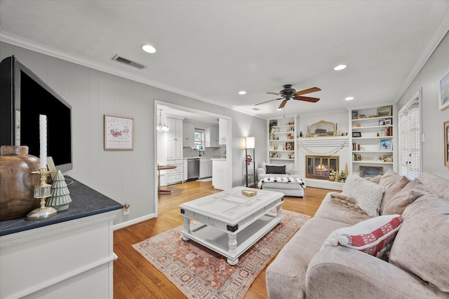 living room featuring crown molding, ceiling fan, and light wood-type flooring