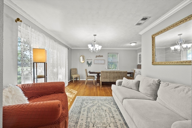 living room with light hardwood / wood-style floors, ornamental molding, and an inviting chandelier