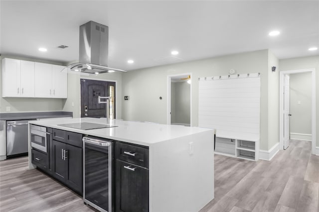 kitchen featuring a center island, stainless steel appliances, beverage cooler, light hardwood / wood-style floors, and island range hood