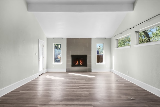 unfurnished living room featuring vaulted ceiling with beams, wood-type flooring, and a tiled fireplace