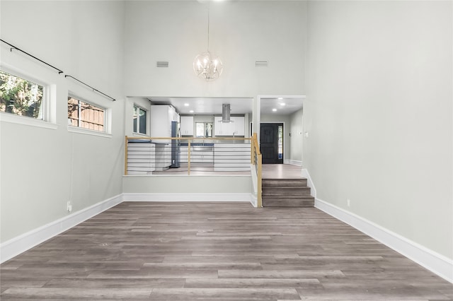 interior space featuring hardwood / wood-style flooring, a towering ceiling, and an inviting chandelier